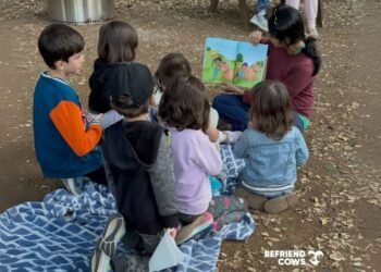 Preethi reading her book to a group of children at a farm animal sanctuary.